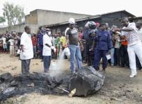 A man extinguishes the burnt remains of a man who was lynched by a mob, as policemen take photographs, in Beni, in the Democratic Republic of Congo's North Kivu province, October 31, 2014.