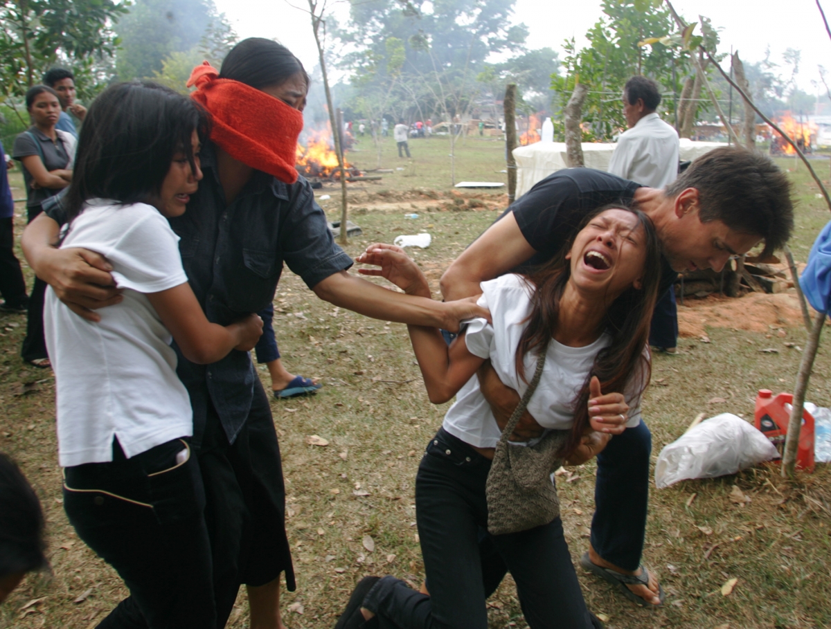 A Swedish man comforts his Thai girlfriend and relatives during the cremation of her relative, who was killed by Sunday's tsunami, in Thap Lamu, Thailand. Swedish Olof Carlsson (R) comforts his Thai girlfriend, Oi, and her relatives during the cremation of her relative, who was killed by Sunday's tsunami, in Thap Lamu, about 900 km (560 miles) south of Bangkok Waves of Tsunami 2004 destroyed countries and killed many people