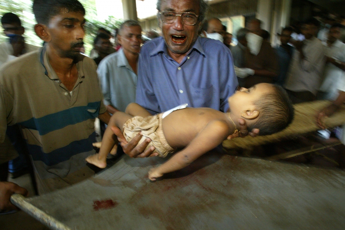 Sri Lankan man cries as he carries the body of a young relative to a hospital in Karapitiya outside Galle. Waves of Tsunami 2004 destroyed countries and killed many people
