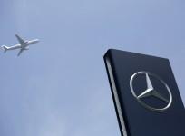 A plane flies above as a Mercedes-Benz logo is seen outside its Shanghai office, August 5, 2014.