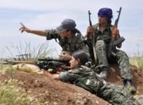 A Kurdish Woman's Protection Unit,YPJ sniper takes position on a hill,while her colleagues watch on.