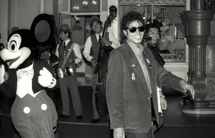 Mickey Mouse follows Michael Jackson as he strolls at a shopping street at the Tokyo Disneyland during his sightseeing tour September 29, 1987 Mickey Mouse Birthday