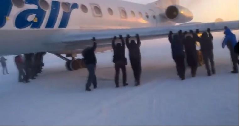 Siberia air passengers had to get out and push their plane stuck in snow. Siberia air passengers had to get out and push their plane stuck in snow