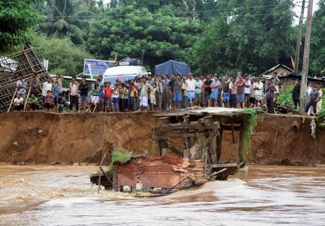 Onlookers stand near a broken bridge which was swept away by flood waters at Goalpara district, after heavy rains in Assam on 23 September 2014. Assam floods