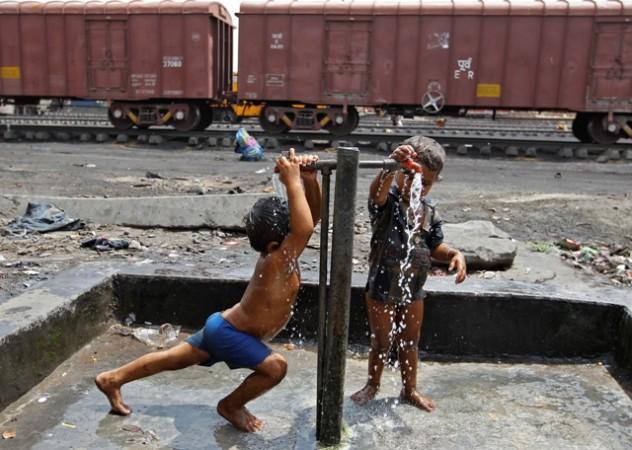 Children of railway workers bathe under water taps installed at a railway goods yard, in Ahmedabad on 8 July 2014. Train labourers