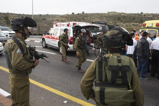 An Israeli soldiers stand as medics evacuate an injured girl from the scene where a Palestinian attacked civilians with a chemical substance near the West Bank Jewish settlement of Neve Daniel, part of the Gush Etzion bloc, December 12, 2014. Palestinian attacked Israeli civilians with a chemical substance near the West Bank Jewish settlement