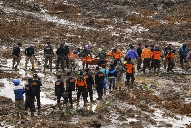 Indonesian soldiers and rescue team members move a dead body after a landslide hit the village of Sampang in Banjarnegara, December 13, 2014 Indonesia landslide