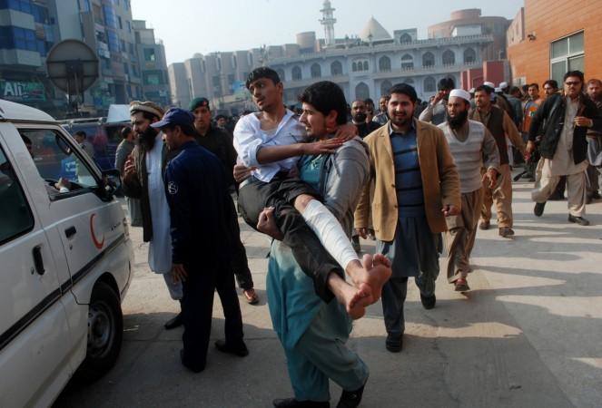 A man carries a student, who was injured during an attack by Taliban gunmen on the Army Public School, after he received treatment at a hospital in Peshawar, December 16, 2014. peshawar attack