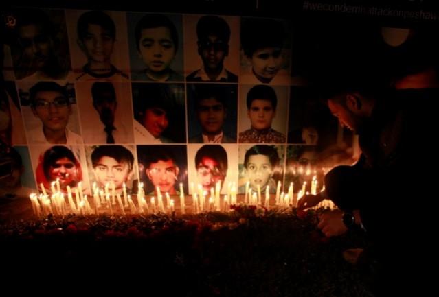 A man places a rose after lighting candles in front of portraits of the victims of the Taliban attack on the Army Public School in Peshawar, during a candlelight vigil in Lahore. Peshawar attack