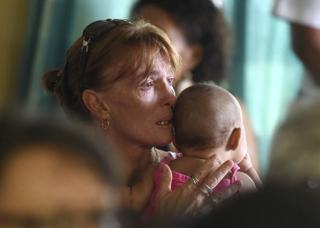 A woman holds her child during a church service for eight children who were killed in the Cairns suburb of Manoora on 21 December. woman arrested for murdering 8 children