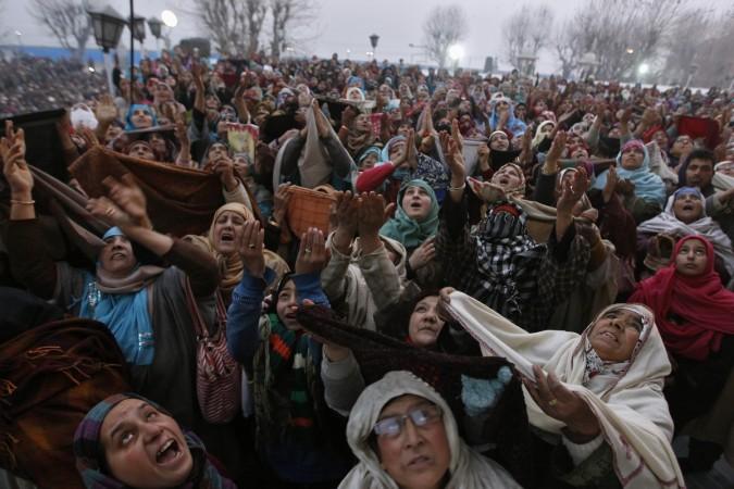 Kashmiri Muslim women raise their arms upon seeing a relic of Prophet Mohammad being displayed to devotees during the festival of Eid-e-Milad, at Hazratbal shrine on a cold winter morning in Srinagar January 4, 2015. Muslims celebrate Eid-e-Milad-un-Nabi 2015