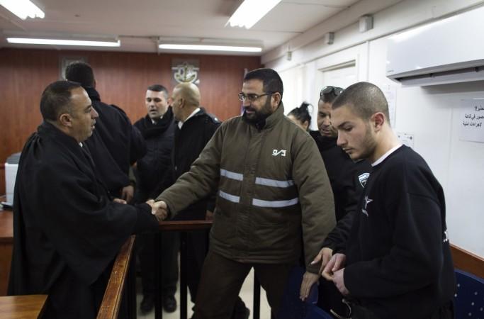 Palestinian Hussam Kawasmeh (C), a member of the militant Hamas Islamist group, shakes hands with his lawyer in a courtroom at Ofer military court near the West Bank city of Ramallah on 6 January, 2015. Palestinian man who started the gaza war sentenced with three life terms
