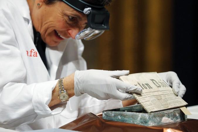 Conservator Pam Hatchfield removes a newspaper from a time capsule, which was placed under a cornerstone of the State House in 1795, at the Museum of Fine Arts, Boston, Massachusetts, January 6, 2015. The capsule dating back to 1795 contained newspaper and coins of various denominations dating as far as 1655.