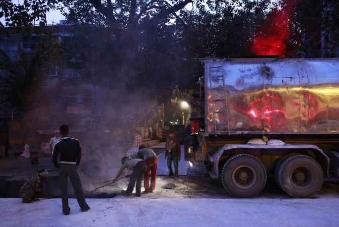 Labourers work during the early morning at the construction site of a road in Mumbai January 2, 2015. Labourers work during the early morning at the construction site of a road in Mumbai January 2, 2015.