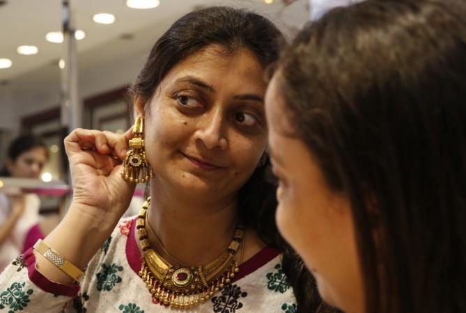 A woman tries on a gold earring inside a jewellery showroom at a market in Mumbai