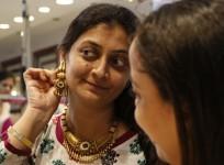 A woman tries on a gold earring inside a jewellery showroom at a market in Mumbai
