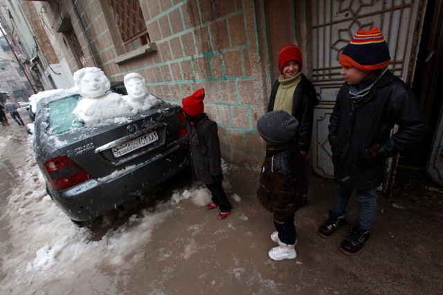 Children look at faces made out of snow placed on a car during a winter storm in the Duma neighbourhood of Damascus. Syria Snow