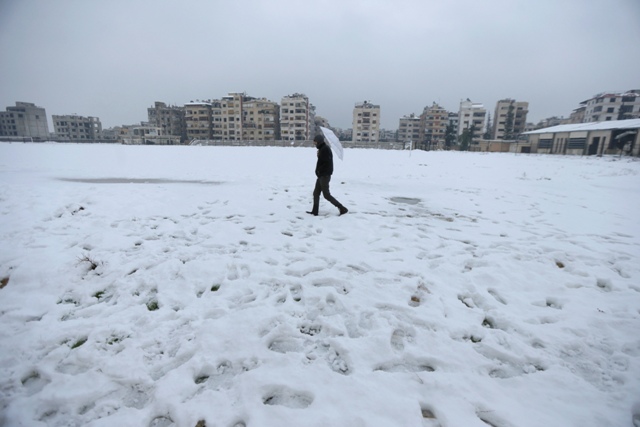 A man holds an umbrella as he makes his way through a road covered with snow in the Duma neighbourhood of Damascus. Syria Snow