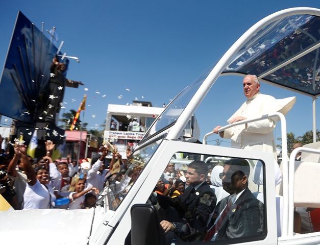 Pope Francis stands on his vehicle as devotees gather on the road to see him after he arrived at the Colombo airport. Pope Francis in Sri Lanka