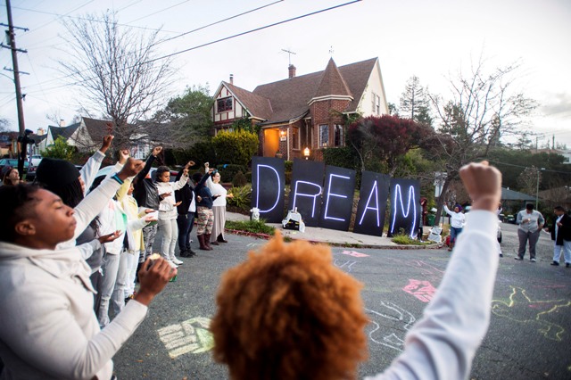 Black rights protesters gather near illuminated letters spelling Martin Luther King Jr. Day Protest