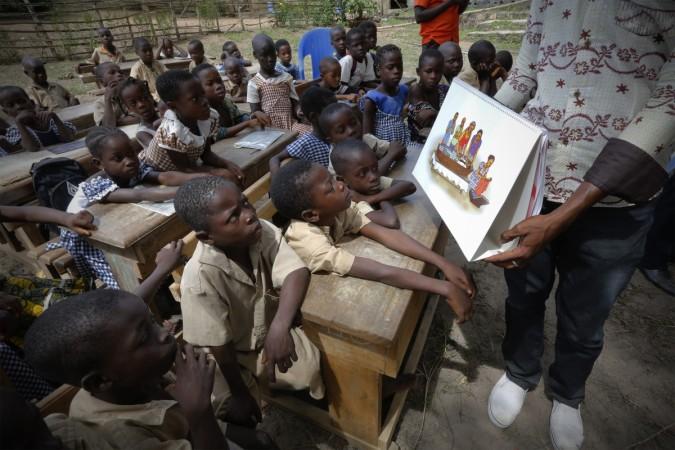 A man shows a picture to students during a United Nations Children's Fund (UNICEF) Ebola awareness drive in Gueupleu, Man, western Ivory Coast. UNICEF Seeks $3.1 Billion in Aid