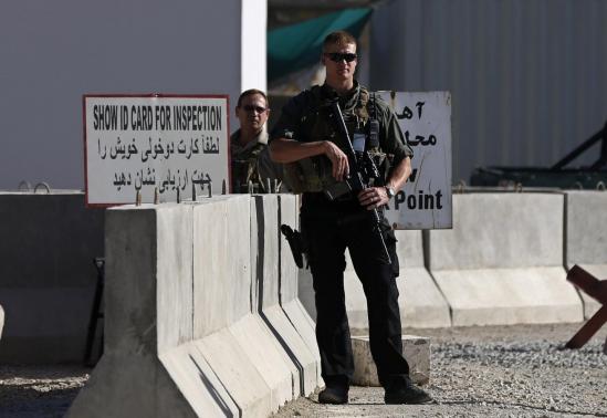 Afghan and foreign security personnel stand guard at the site of a blast, outside the counter-narcotics office near the Kabul International Airport