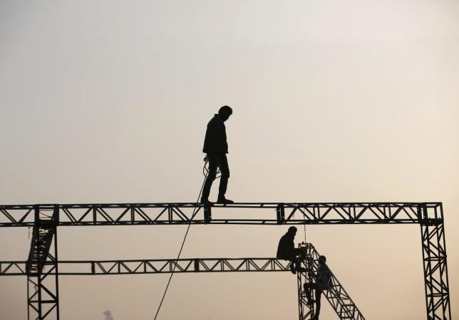 Workers are silhouetted against the rising sun as they prepare to install a temporary tent in the western Indian city of Ahmedabad January 22, 2015. Indian Worker