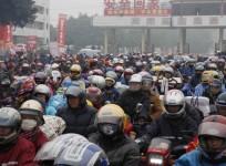 Migrant workers ride their motorcycles with families and friends, as they past a checkpoint on their way home for the upcoming Spring Festival, on a hazy day in Fengkai county, Guangdong province, February 12, 2015