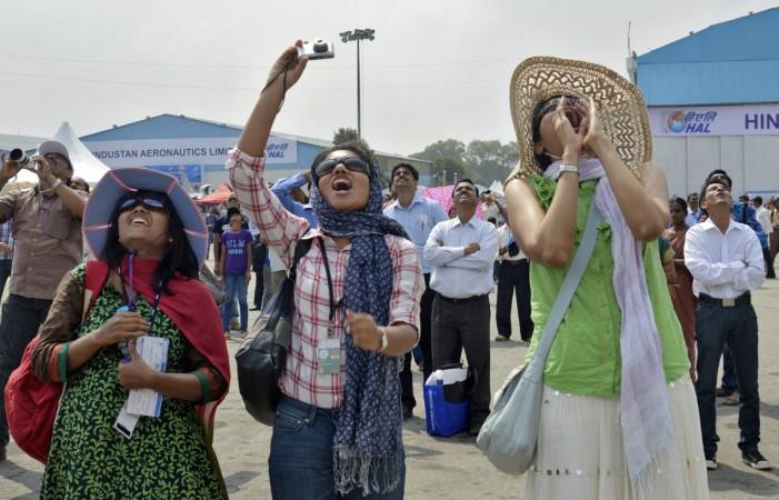 Visitors cheer as they watch Russian Knights, the aerobatic team of the Russian Air Force, performing in their Sukhoi Su-27 and Su-27UB fighter aircraft during Aero India Bangalore
