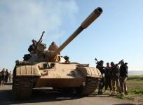 Kurdish Peshmerga fighters walk next to their tank as they take control of the area, on the outskirts of Mosul February 6, 2015.