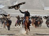 Herdsmen from the Kyrgyz ethnic group hold their falcons as they ride on horses during a performance to celebrate the Nowruz festival