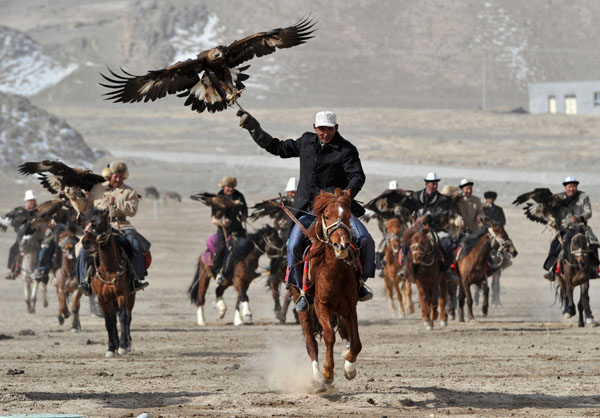 Herdsmen from the Kyrgyz ethnic group hold their falcons as they ride on horses during a performance to celebrate the Nowruz festival