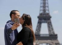 A couple of tourists use a mobile phone to take a selfie picture as they kiss at the Trocadero Square near the Eiffel Tower in Paris, May 16, 2014.