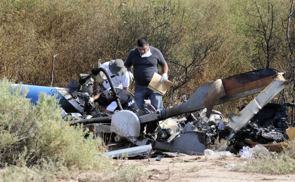 Investigators work next to the charred wreckage of the two helicopters which collided in the region of Villa Castelli, in the Argentine province of La Rioja on 10 March 2015. Argentina Helicopter Crash