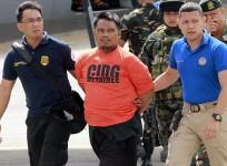 Members of the Philippine National Police (PNP) intelligence escort Mohammad Ali Tambako (C), founder and leader of the Justice Islamic Movement, upon arrival at Villamor Air Base in Manila March 16, 2015.