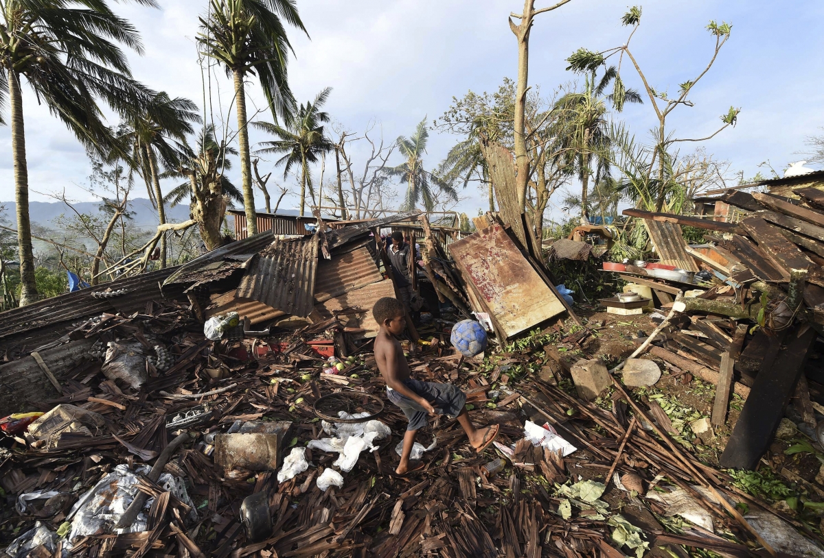 A boy called Samuel kicks a ball as his father Phillip searches through the ruins of their home which was destroyed by Cyclone Pam in Port Vila, the capital city of the Pacific island nation of Vanuatu March 16, 2015. Vanuatu cyclone Pam