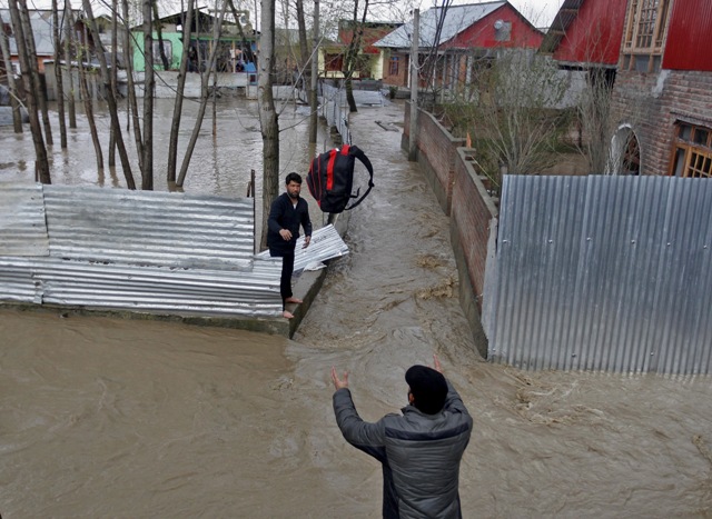 A man throws his belongings towards another to be moved to a safer place at a flooded neighbourhood after incessant rains in Srinagar. Kashmir Floods