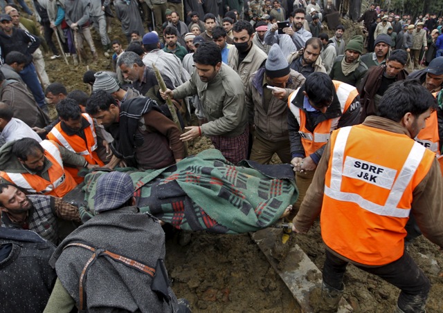 Villagers and rescue workers carry the body of a victim amongst the rubble after a hillside collapsed onto a house at Laden village. Kashmir Floods