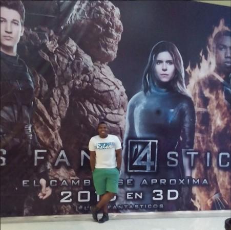 A fan posing in front of the poster of the upcoming movie of Fantastiv Four