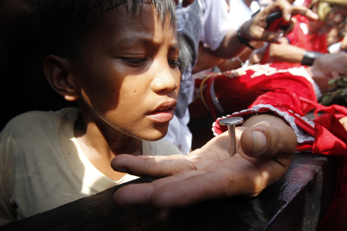 A boy looks at the palm of a penitent nailed on a wooden cross during a reenactment of Jesus Christ's crucifixion on Good Friday in Barangay Cutud, San Fernando, Pampanga in northern Philippines April 6, 2012 A boy looks at the palm of a penitent nailed on a wooden cross during a reenactment of Jesus Christ's crucifixion on Good Friday in Barangay Cutud, San Fernando, Pampanga in northern Philippines April 6, 2012