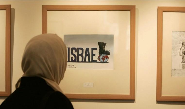 An Iranian woman looks at an entry from the International Holocaust Cartoon Contest in Tehran on Aug. 14, 2006. (Raheb Homavandi/Reuters)