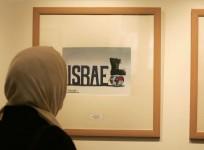 An Iranian woman looks at an entry from the International Holocaust Cartoon Contest in Tehran on Aug. 14, 2006. (Raheb Homavandi/Reuters)