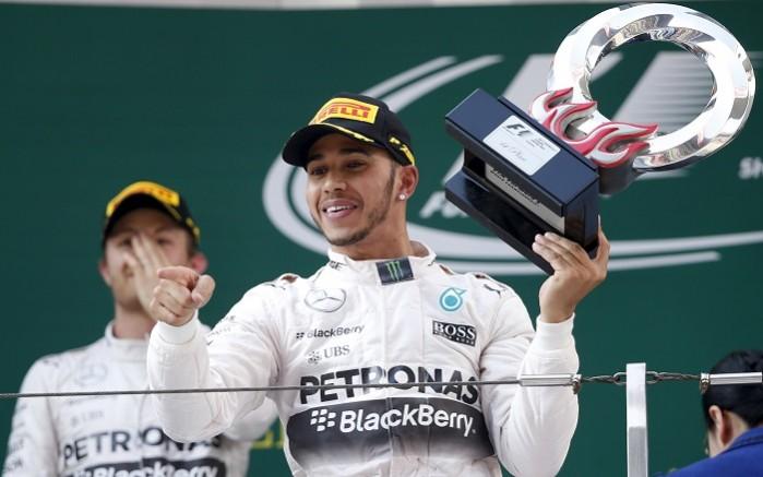 Mercedes driver Lewis Hamilton of Britain (R) gestures with his trophy as he celebrates his victory in front of his team mate second placed Nico Rosberg of Germany on the podium after the Chinese Grand Prix at the Shanghai International Circuit Chinese Grand Prix
