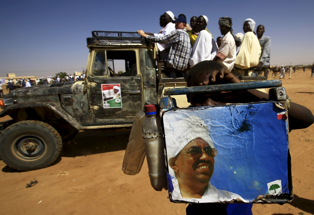 A shoe cleaner holds a picture of National Congress Party's (NCP) presidential candidate, Sudan's President Omar Hassan al-Bashir during a campaign rally at Al Fashir in North Darfur, April 8, 2015. Sudan elections
