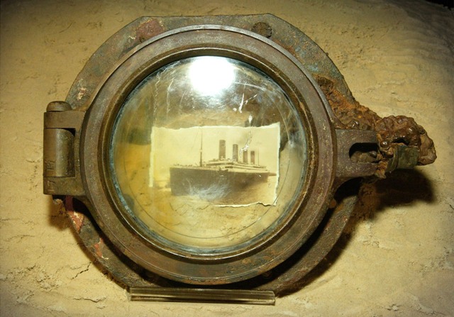 A photograph of the Titanic is seen through a porthole belonging to the ship on display at The Science Museum in London. The Titanic Remains