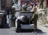 An Israeli soldier searches a Palestinian vehicle at a checkpoint near Hebron