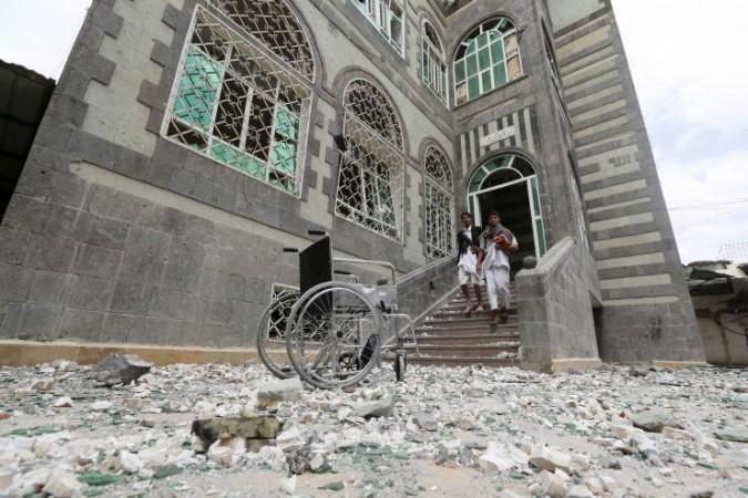 People walk out of their house damaged by an air strike in Sanaa April 8, 2015