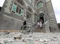 People walk out of their house damaged by an air strike in Sanaa April 8, 2015