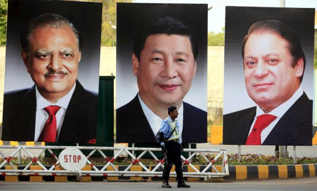 A policeman stands guard next to giant portraits of (L-R) Pakistan's President Mamnoon Hussain, China's President Xi Jinping, and Pakistan's Prime Minister Nawaz Sharif, displayed along a road ahead of Xi's visit to Islamabad April 19, 2015