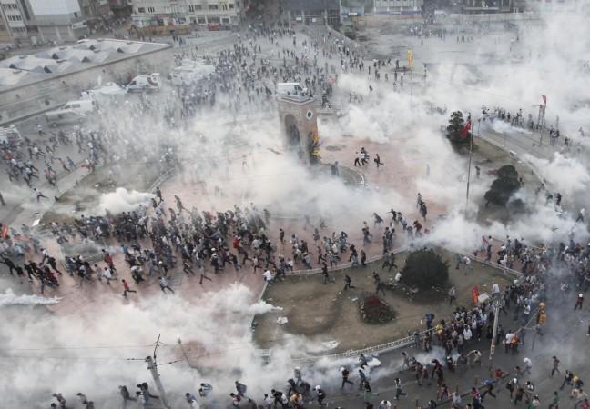 Protesters run as riot police fire teargas during a protest at Taksim Square in Istanbul June 11, 2013